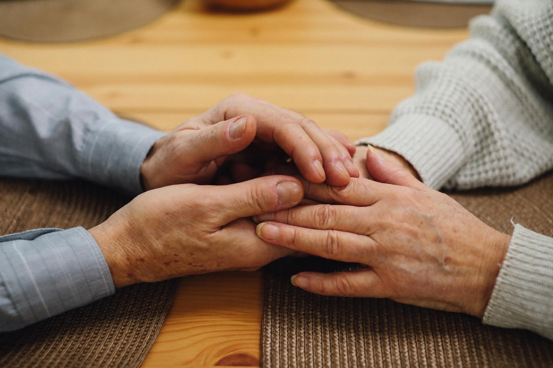 close up photo of an elderly couple holding hands
